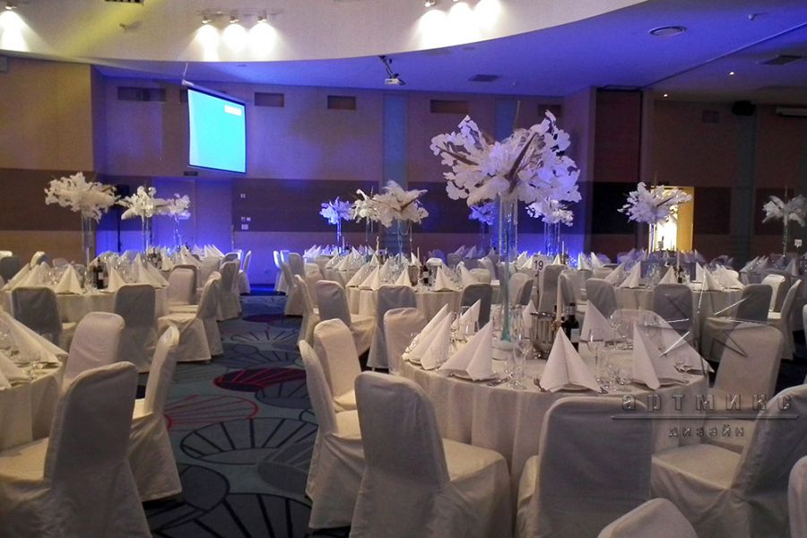 Новогоднее оформление зала высокими вазами с композициями из перьев и веточками Гинкго